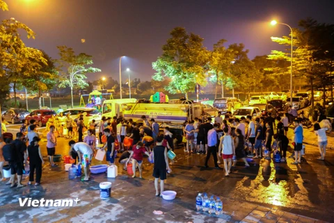 Ngay trong đêm 16 rạng sáng 17/10, hàng trăm hộ dân trong Khu đô thị Nam An Khánh (Hoài Đức, Hà Nội) đã mang theo xô, chậu tấp nập xếp hàng, chờ đến lượt nhận nước sạch về sinh hoạt. (Ảnh: Minh Sơn/Vietnam+)