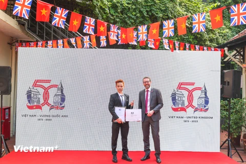 Đại sứ Anh tại Việt Nam Iain Frew trao kỷ niệm chương cho Ngô Quang Trung, tác giả mẫu logo kỷ niệm 50 năm quan hệ ngoại giao Vương quốc Anh - Việt Nam. (Ảnh: Minh Sơn/Vietnam+)