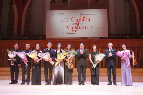 Đại sứ Canada tại Việt Nam David Devine tặng hoa cho các nghệ sỹ. (Ảnh: Hữu Đức/Vietnam+)