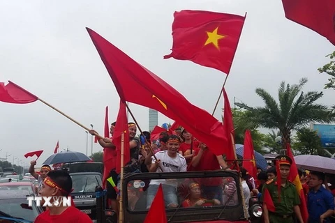 Trên dọc tuyến đường vào sân bay quốc tế Nội Bài, rất đông người hâm mộ đã đeo băng rôn và mang cờ hoa ra đón các cầu thủ Đội tuyển Olympic Việt Nam. (Nguồn: Quang Quyết/TTXVN)