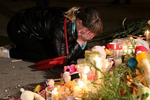 Một người phụ nữ đổ gục trong nước mắt tại lễ tưởng niệm các nạn nhân. (Nguồn: Daily Mail)