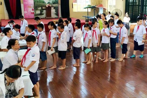 Cán bộ y tế quận Hoàng Mai phối hợp cùng các cán bộ y tế trên địa bàn khám sức khỏe định kỳ cho học sinh.(Nguồn: Cổng thông tin điện tử chính phủ)