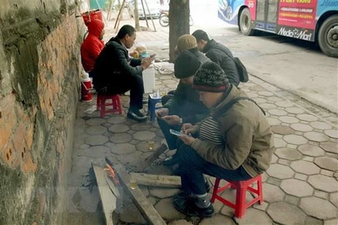 Người dân trên phố Trần Khánh Dư đốt củi để sưởi ấm. (Ảnh: Quang Quyết-TTXVN)