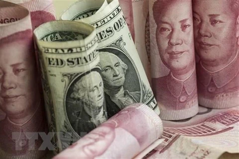 Đồng nhân dân tệ và đồng USD tại một ngân hàng ở Bắc Kinh, Trung Quốc. (Ảnh: AFP/TTXVN)