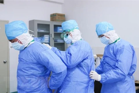 Các nhân viên y tế giúp đỡ nhau mặc quần áo bảo hộ tại khu vực cách ly điều trị cho bệnh nhân nhiễm virus corona của bệnh viện ở Chương Châu, tỉnh Phúc Kiến, Trung Quốc. (Ảnh: THX/TTXVN)