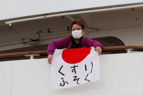 Một hành khách người Nhật Bản giơ quốc kỳ in dòng chữ "Thiếu thuốc men." (Ảnh: Reuters)