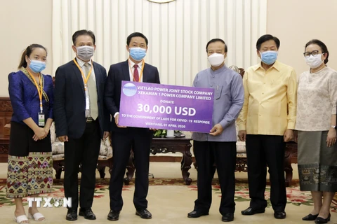 Ông Đinh Ngọc Diệp, Trưởng Đại diện Công ty CP điện Việt Lào (trái) và Phó Thủ tướng, Bộ trưởng Tài chính Lào Somdy Duangdy (Phải) tại lễ trao tiền ủng hộ. (Ảnh: PV/TTXVN)