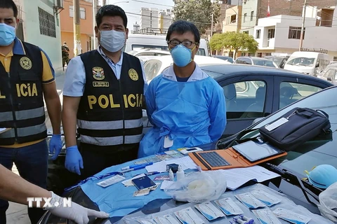 Đối tượng Tianxing Zhang (phải) bị bắt giữ do tiến hành xét nghiệm COVID-19 bất hợp pháp tại Lima , Peru, ngày 12/4/2020. (Ảnh: AFP/TTXVN)