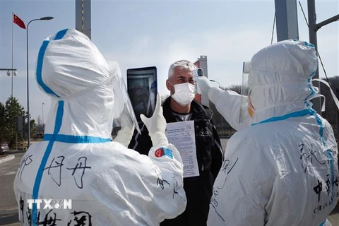 Nhân viên y tế Trung Quốc kiểm tra thân nhiệt ngăn chặn sự lây lan của dịch COVID-19 tại một trạm kiểm tra hải quan ở Suifenhe, tỉnh Hắc Long Giang, gần biên giới với Nga, ngày 1/5/2020. (Ảnh: AFP/TTXVN)