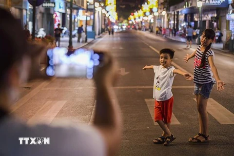 Người dân Thủ đô ghi lại những hình ảnh đáng nhớ trên phố đi bộ hồ Hoàn Kiếm ngày hoạt động trở lại. (Ảnh: Thành Đạt/TTXVN)