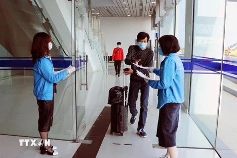 Lực lượng thanh niên tình nguyện hỗ trợ hành khách khai báo thông tin y tế. (Ảnh: Hoàng Ngọc/TTXVN)