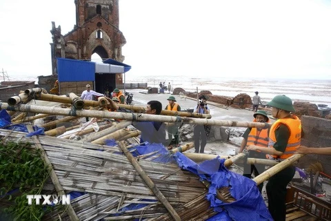 Cán bộ đồn Biên phòng Văn Lý giúp người dân khắc phục sau bão số 1 đi qua tại khu vực bãi biển xã Hải Lý (Hải Hậu). (Ảnh: Minh Quyết/TTXVN)