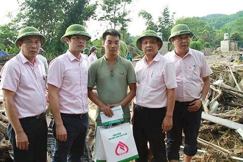 Phó Tổng Giám đốc Nguyễn Đức Hải (thứ hai từ trái sang) cùng đoàn công tác hăm hỏi động viên gia đình ông Hà Văn Liều ở bản Tủ, xã Sơn Lương có nhà bị sập. (Nguồn: Ngân hàng Chính sách)