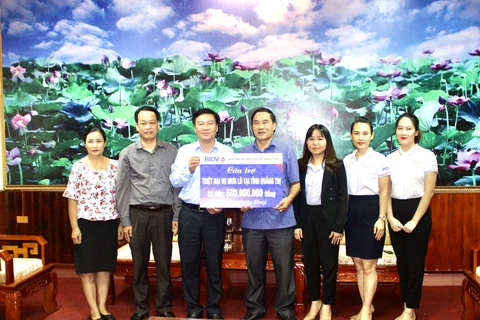Lãnh đạo BIDV trao số tiền ủng hộ cho đại diện 2 tỉnh. (Ảnh: Vietnam+)