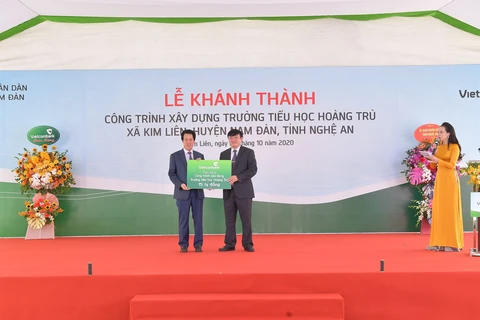 Ông Nguyễn Mỹ Hào-thành viên HĐQT Vietcombank trao biển tượng trưng số tiền 15 tỷ đồng tài trợ xây dựng Trường tiểu học Hoàng Trù. (Ảnh: Vietnam+)