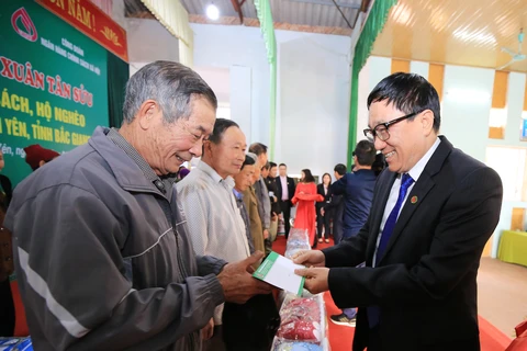 Tổng Giám đốc NHCSXH Dương Quyết Thắng tặng quà cho các gia đình có công với cách mạng, gia đình chính sách và hộ nghèo tại xã Lam Cốt. (Ảnh: CTV/Vietnam+)