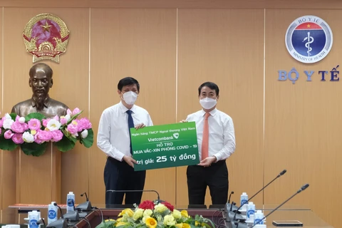 Đại diện Vietcombank, ông Nghiêm Xuân Thành - Chủ tịch HĐQT Vietcombank (bên phải) đã trao 25 tỷ đồng hỗ trợ mua vắc xin phòng COVID-19 cho Bộ trưởng Bộ Y tế Nguyễn Thanh Long. (Ảnh: Vietnam+)