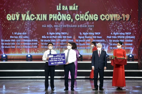 Ông Nghiêm Xuân Thành - Chủ tịch HĐQT Vietcombank (thứ 2 từ trái sang) trao biển ủng hộ 60 tỷ đồng cho Quỹ vaccine phòng, chống COVID-19. (Ảnh: Vietnam+)