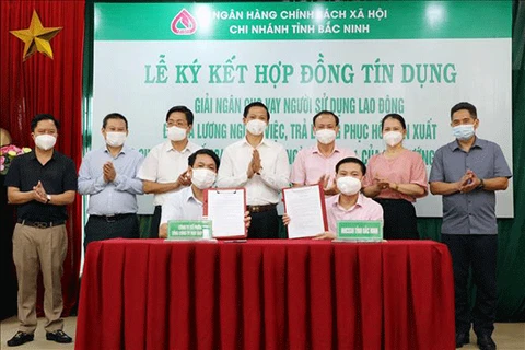 Chi nhánh NHCSXH tỉnh Bắc Ninh ký hợp đồng tín dụng, giải ngân cho vay Công ty cổ phần May Đáp Cầu và Công ty TNHH Viet Pacific Clothing. (Ảnh: Vietnam+)