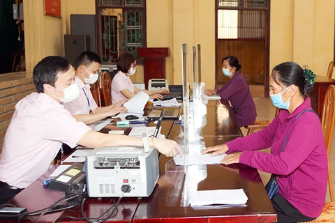 Các đối tượng chính sách ở xã Phù Linh, huyện Sóc Sơn (Hà Nội) đến Điểm giao dịch của Ngân hàng Chính sách xã hội tại trụ sở UBND xã làm thủ tục, nhận vốn vay.