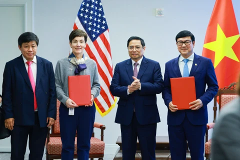 Bà Stephanie von Friedeburg - Phó Chủ tịch điều hành cao cấp IFC (thứ 2 từ trái sang) và ông Trần Hoài Nam - Phó Tổng giám đốc HDBank (bìa phải) trao văn kiện ký kết dưới sự chứng kiến của Thủ tướng Chính phủ Phạm Minh Chính. (Ảnh: Vietnam+)