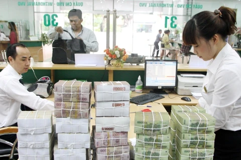 Giao dịch tiền mặt tại Vietcombank. (Ảnh: Vietnam+)