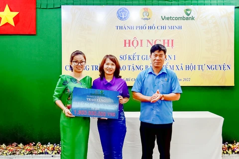 Bà Lê Thị Hòa Bình - Phó Giám đốc Vietcombank Thành phố Hồ Chí Minh (bên trái) trao bảng tượng trưng tái tục bảo hiểm xã hội trị giá 1,8 tỷ đồng cho đại diện đoàn viên các nghiệp đoàn nhận bảo hiểm xã hội năm 2021. (Ảnh: Vietnam+)