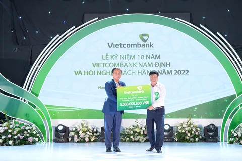 Ông Nguyễn Việt Cường - Phó Tổng Giám đốc trao biển tượng trưng số tiền ủng hộ của Vietcombank để xây dựng trường Trung học cơ sở xã Nam Thanh, huyện Nam Trực, tỉnh Nam Định. (Ảnh: Vietnam+)