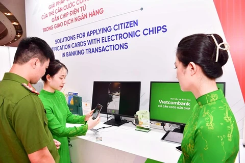 Cán bộ Vietcombank giới thiệu ứng dụng căn cước công dân gắn chip. (Ảnh: Vietnam+)