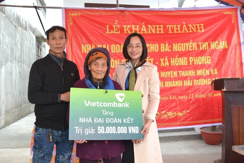 Bà Phạm Minh Đào - Phó Giám đốc Vietcombank Hải Dương (ngoài cùng bên phải) trao biển tặng nhà đại đoàn kết cho gia đình bà Nguyễn Thị Ngận, hộ nghèo thuộc huyện Thanh Miện, tỉnh Hải Dương. (Ảnh: Vietnam+)