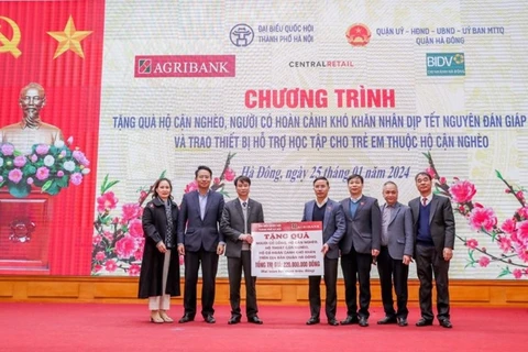 Ông Phạm Đức Ấn - Chủ tịch Hội đồng thành viên Agribank trao tặng quà của Agribank hỗ trợ hộ cận nghèo, đối tượng chính sách quận Hà Đông (Hà Nội) nhân dịp Tết Nguyên đán Giáp Thìn. (Ảnh: Vietnam+)