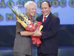 Phó Thủ tướng Nguyễn Xuân Phúc tặng hoa chúc mừng nguyên Phó Thủ tướng Vũ Khoan, tác giả đoạt giải B năm 2011. (Ảnh: Thanh Tùng/TTXVN)