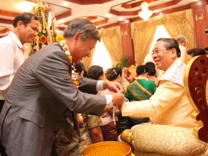 Đại sứ Nguyễn Mạnh Hùng đã buộc chỉ cổ tay chúc phúc cho Tổng Bí thư, Chủ tịch nước Lào Chummaly Saynhasone. (Ảnh: Hoàng Chương/Vietnam+)