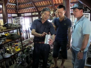 Cựu chiến binh Nguyễn Hữu Ích giới thiệu kỷ vật với khách tham quan. (Ảnh: Vũ Văn Đạt/Vietnam+)