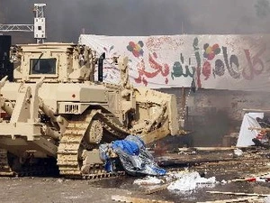 Xe ủi đi qua khu trại của những người biểu tình bị đốt cháy ở Cairo ngày 14/8 sau khi lực lượng an ninh giải tán những người biểu tình. (Nguồn: AFP/TTXVN)