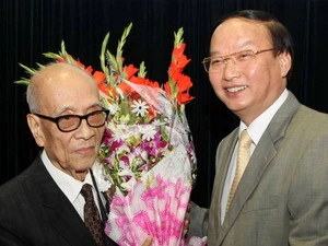 Ông Tô Huy Rứa (phải), Ủy viên Bộ Chính trị, Trưởng Ban Tuyên Giáo Trung ương, tặng hoa chúc mừng sinh nhật giáo sư Vũ Khiêu. (Ảnh: Nhật Anh/TTXVN)