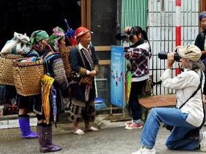 Du khách nước ngoài chụp ảnh đồng bảo dân tộc ở Sa Pa. (Ảnh: Thanh Hà/TTXVN)