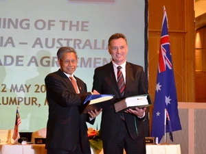Bộ trưởng Công nghiệp và Thương mại quốc tế Malaysia Mustapa Mohamed và Bộ trưởng Thương mại và Cạnh tranh Australia Craig Emerson MP trao đổi tài liệu sau lễ ký. (Ảnh: Xuân Triển/Vietnam+)