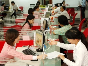Khách hàng làm thủ tục gửi tiền tiết kiệm tại NHTM cổ phần Kỹ Thương Việt Nam. (Ảnh: Trần Việt/TTXVN)
