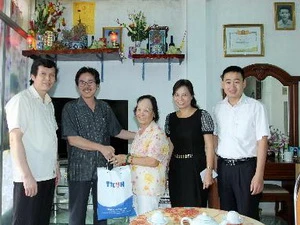 Ông Ngô Hà Thái, Phó Tổng Giám đốc Thông tấn xã Việt Nam, tặng quà cho bà Phương Bích Ngân là vợ Nhà báo liệt sỹ Thẩm Đức Hòa. (Ảnh: An Đăng/TTXVN)