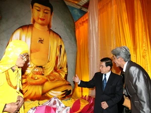 Chủ tịch nước Nguyễn Minh Triết xem phiến đá ngọc bích để chế tác tương Phật tổ Thích ca Mâu Ni. (Ảnh: Nguyễn Khang/TTXVN) 