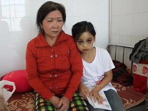 Bé Phi cùng mẹ nuôi, bà Đoàn Thị Hồng Yến trong Bệnh viện Đa khoa tỉnh Quảng Ngãi. (Nguồn: Báo Quảng Ngãi Online)