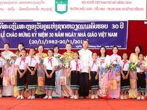 Các em học sinh tặng hoa va chụp ảnh chung với các thầy, cô giáo. (Ảnh: Hoàng Chương/Vietnam+)