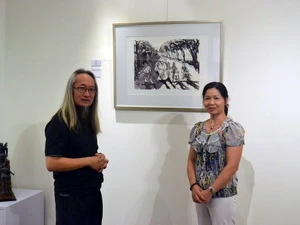 Họa sỹ Singapore, Choo Meng Foo (trái) giới thiệu với khách tham quan về tác phẩm của mình. (Ảnh: Chí Giáp/Vietnam+)