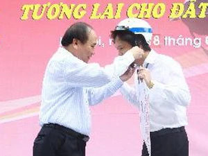 Phó Thủ tướng Nguyễn Xuân Phúc đội mũ bảo hiểm cho đại diện cán bộ, công nhân viên Tổng Công ty May 10. (Ảnh: Doãn Tấn/TTXVN)