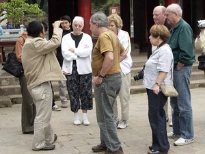 Hướng dẫn viên du lịch giới thiệu với du khách nước ngoài về một di tích ở Hà Nội. (Nguồn: TTXVN)