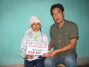 Đại diện Quỹ từ thiện "Trái tim cho quê hương" trao tiền hỗ trợ cho một người dân khó khăn ở Nam Định. (Nguồn: dvmk.org)