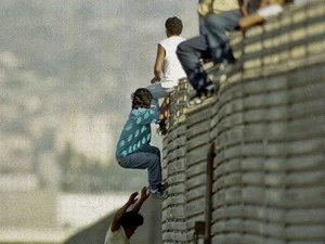 Một nhóm người đang trèo qua hàng rào biên giới để vào Mỹ. Ảnh minh họa. (Nguồn: AP)