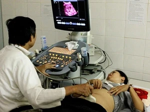 Bác sỹ kiểm tra sức khỏe cho thai phụ. (Ảnh: TTXVN)
