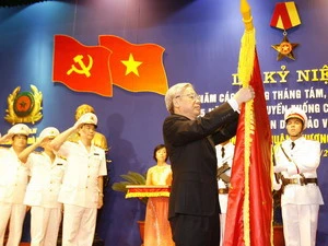 Chủ tịch Quốc hội Nguyễn Phú Trọng gắn Huân chương Sao Vàng lên lá cờ truyền thống của Công an thành phố Hà Nội. (Ảnh : Trí Dũng/TTXVN)